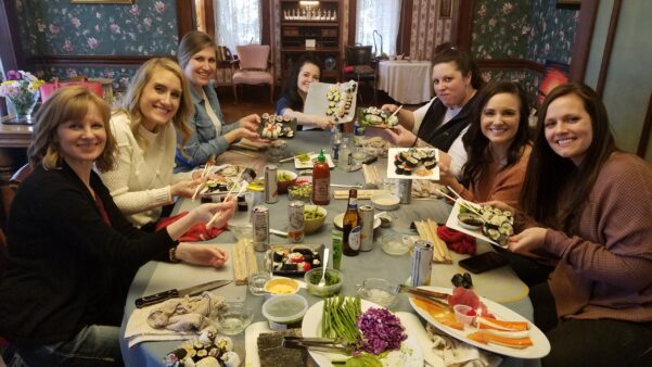 Group of ladies showing off their completed sushi rolls.